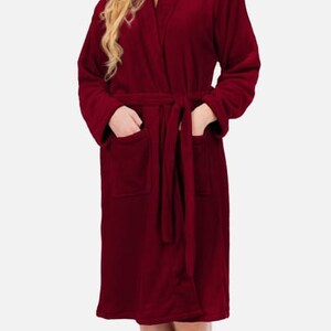 May include: A long-sleeved, burgundy robe with a shawl collar and a tie belt. The robe has two pockets on the front.