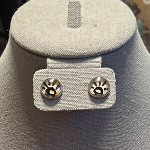 May include: A pair of silver stud earrings with a sunburst design.