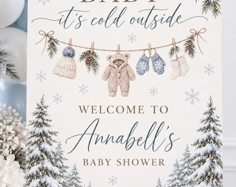 Peut inclure: Une affiche rectangulaire avec le texte BABY it's cold outside et WELCOME TO Annabell's BABY SHOWER. Le design présente des illustrations de branches de pin, de pommes de pin, de flocons de neige et une corde à linge avec un bonnet, une combinaison.