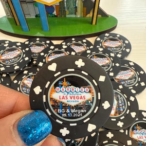 May include: Black poker chips with a white border and a design featuring the Las Vegas sign and the text "Married in Fabulous Las Vegas, Nevada" with the couple's names and wedding date.