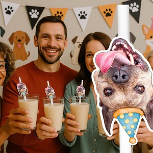 Op de afbeelding: Een groep mensen lacht en houdt glazen vast met een romige drank, met decoraties met hondenthema op de achtergrond. De afbeelding toont een grote hondenuitsparing met een feesthoed. De drankjes hebben roerstaafjes met hondenthema.