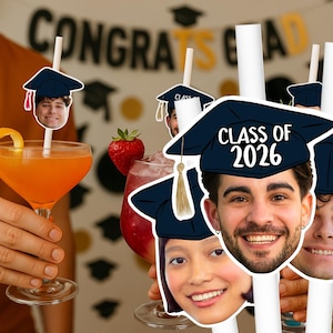 Op de afbeelding: Cocktails met afstudeer-thema decoraties. De drankjes zijn gegarneerd met sinaasappelschillen en aardbeien. De rietjes hebben gezichten en afstudeerpetten met de tekst "Class of 2026". De achtergrond zegt "Congrats Grad".