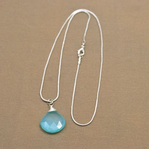 May include: A silver chain necklace with a light blue teardrop-shaped gemstone pendant.