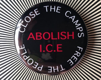 May include: A black and white button with the text "CLOSE THE CAMPS FREE THE PEOPLE" in white and "ABOLISH I.C.E" in red.