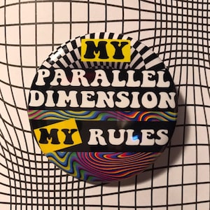 Könnte beinhalten: Ein schwarzer und gelber Knopf mit einem psychedelischen Design. Der Knopf sagt "My Parallel Dimension My Rules".