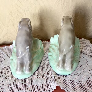 May include: A pair of ceramic bookends featuring gray elephants standing on a green base. The elephants are facing opposite directions.