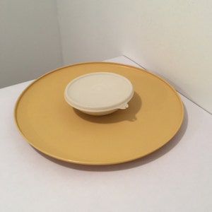 May include: A yellow plastic serving tray with a white plastic bowl and lid on top.