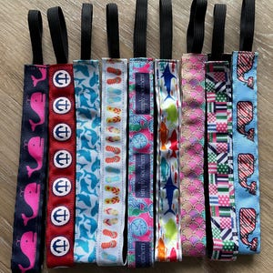 May include: Nine colorful hair ties with different patterns, including anchors, flip flops, fish, and seashells. The hair ties are made of elastic and have a black elastic band.