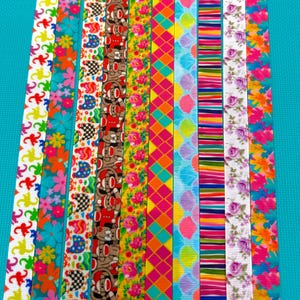 May include: A collection of ten vertical fabric ribbons featuring diverse patterns including colorful flowers, monkeys, geometric diamonds, stripes, and scalloped shapes in a vibrant palette of pink, yellow, blue, green, and brown hues.
