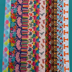 May include: A collection of eleven vertical ribbons featuring diverse patterns including pink seashells, colorful flowers, flamingos, rainbow stripes, chickens, pumpkins, cowboy boots, jack-o'-lanterns, turkeys, elves, and orange letters.