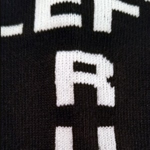 May include: Close-up of a black sock with white lettering that reads "LEFT ARM".
