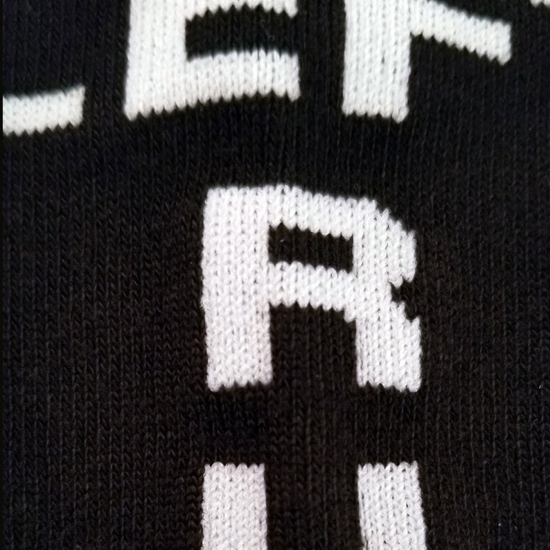 May include: Close-up of a black sock with white lettering that reads "LEFT ARM".