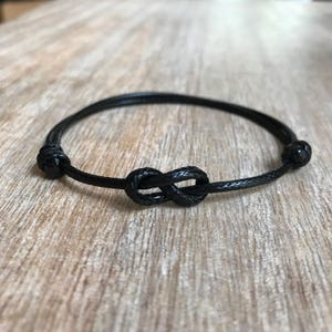 May include: A black cord bracelet with an infinity knot design.