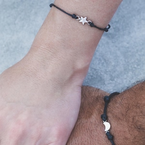 May include: Two matching bracelets with black cord and silver charms. One bracelet has a star charm, the other has a crescent moon charm.