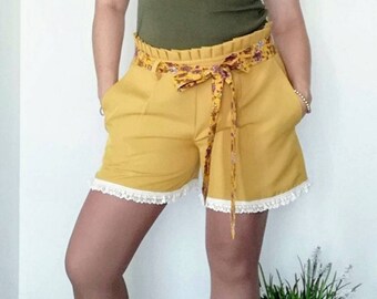 Handmade women's shorts in mustard yellow with lace details, floral belt and pleated effect at the waist