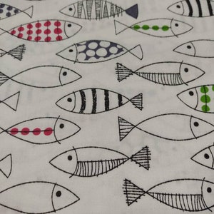 May include: White fabric with a repeating pattern of black and white fish with various colored details. The fish have black eyes, black outlines, and some have red, blue, or green polka dots.