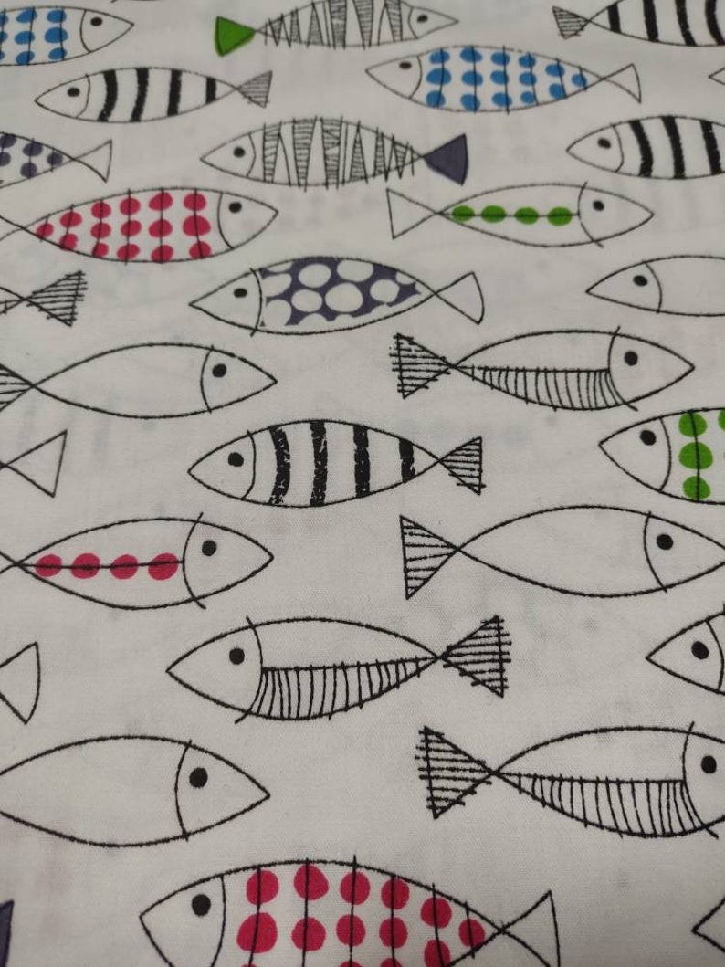 May include: White fabric with a repeating pattern of black and white fish with various colored details. The fish have black eyes, black outlines, and some have red, blue, or green polka dots.