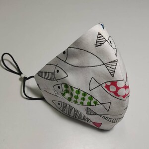 May include: White face mask with a black and white fish pattern. The fish have green and red polka dots.