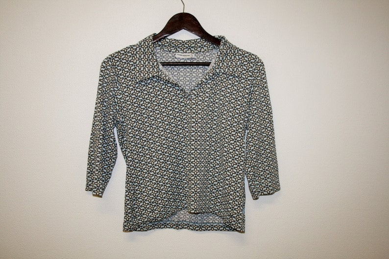 May include: A white, long-sleeved shirt with a geometric pattern in shades of blue and green. The shirt has a collar and a button-up front.