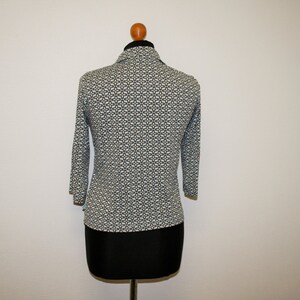 May include: A white and blue patterned long-sleeve shirt with a collared neckline. The shirt is on a mannequin.