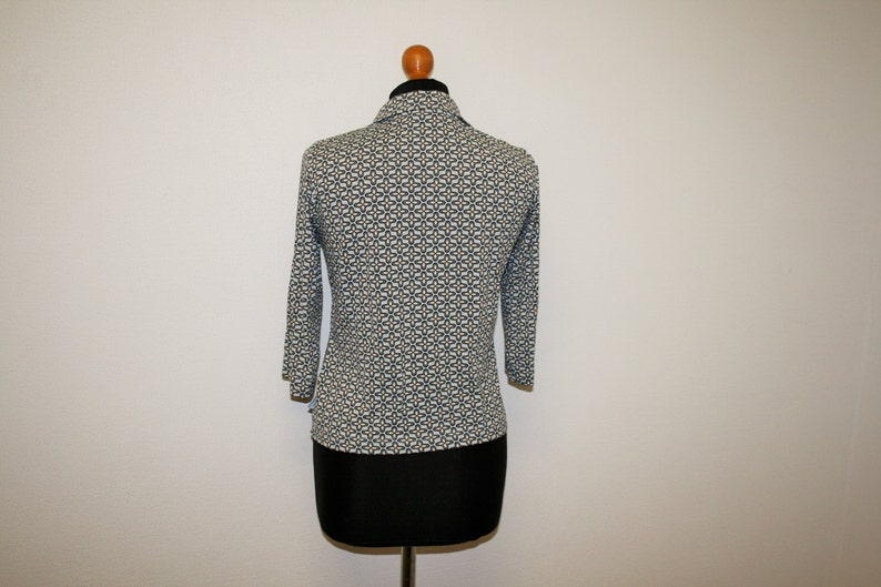 May include: A white and blue patterned long-sleeve shirt with a collared neckline. The shirt is on a mannequin.
