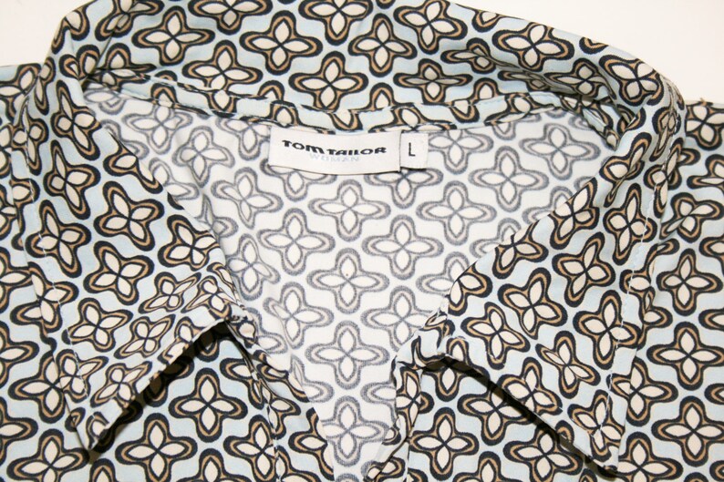 May include: A blue and white patterned shirt with a collar. The shirt has a label that says "TOM TAILOR" and "L" for size.