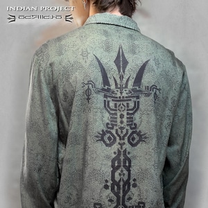 May include: A green long-sleeved shirt with a black geometric design on the back. The design features a large, intricate pattern with a central vertical element.