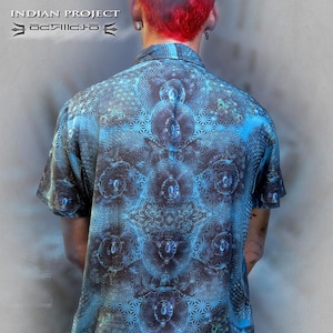 Puede incluir: Una camisa azul de manga corta con un patrón geométrico. La camisa tiene cuello y cierre de botones. El patrón es un diseño complejo de círculos y líneas.