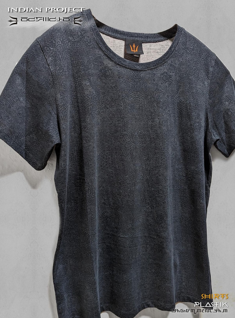 Puede incluir: Una camiseta gris oscura con un patr&oacute;n geom&eacute;trico blanco. La camiseta tiene cuello redondo y mangas cortas. El texto "SHIRTS PLASTIK" es visible en la parte inferior de la imagen.