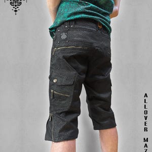 Könnte beinhalten: Schwarze Cargo-Shorts mit einem Labyrinthmuster und mehreren Reißverschlusstaschen. Die Shorts werden mit einem gemusterten grünen Oberteil getragen. Der Text "ALLOVER MAZE" und "PSYCUE" sind sichtbar.