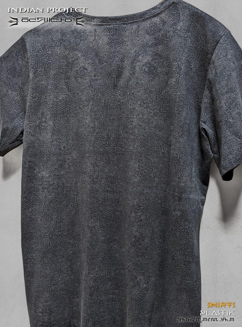 Puede incluir: Una camiseta gris oscura con un patr&oacute;n geom&eacute;trico blanco por toda la superficie. La camiseta tiene cuello redondo y mangas cortas. El texto "INDIAN PROJECT" est&aacute; impreso en la parte superior de la camiseta.