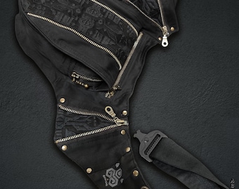 May include: A black holster bag featuring multiple zippered compartments, metallic studs, and intricate tonal embroidery. The bag includes an adjustable strap with a plastic buckle and displays the text OLSTER BAGS INDIAN PROJECT.