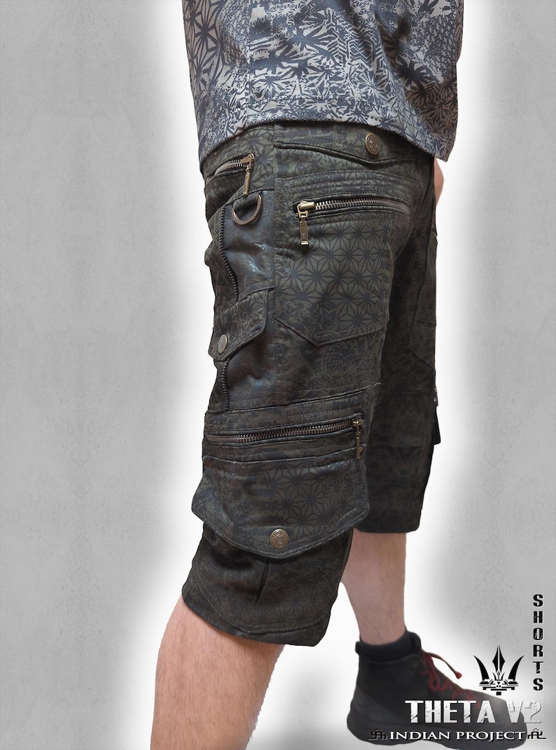 May include: Dark charcoal cargo shorts featuring a repeating geometric star pattern, multiple zippered pockets, metal D-ring hardware, and snap-button closures. The shorts include a side pocket design and are paired with a matching patterned shirt.