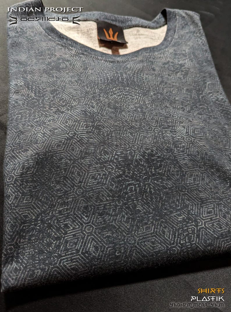 Puede incluir: Una camiseta gris oscura con un patr&oacute;n geom&eacute;trico blanco. La camiseta tiene cuello redondo y est&aacute; hecha de una tela suave y c&oacute;moda. El texto "INDIAN PROJECT" est&aacute; impreso en la parte superior de la camiseta.