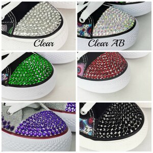 May include: Close-up of six different bedazzled sneakers. Each sneaker has a white rubber sole and white laces. The toe caps are covered in clear, clear AB, green, red, purple, and black rhinestones. The text "Clear" and "Clear AB" are visible.