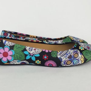 May include: Black ballet flats with a colorful Day of the Dead print featuring skulls, flowers, and leaves.