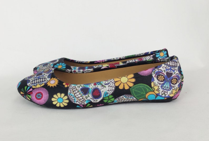 May include: Black ballet flats with a colorful Day of the Dead sugar skull and floral print.