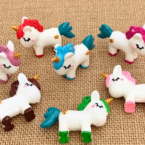 May include: Set of ten small white unicorn figurines with colourful accents. Each unicorn has a different coloured mane and tail, including pink, blue, green, and purple. The unicorns have gold horns and hooves.