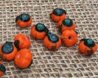 Puede incluir: Una colección de cuentas de calabaza de vidrio naranja y verde. Las cuentas tienen un diámetro de aproximadamente 2,5 cm y un acabado brillante.