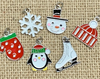 May include: Seven silver charms with enamel paint depicting winter holiday themes. The charms include a snowman, a snowflake, a mitten, a penguin, a hat, and a pair of ice skates.