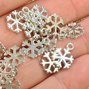 May include: A collection of silver snowflake charms with a loop for attaching to jewelry or other crafts.