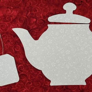 May include: White tea pot and tea bag cutouts on a red background with a swirling pattern.