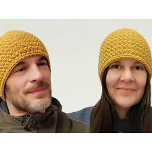 May include: Two people wearing mustard yellow crocheted beanies. The beanies have a textured stitch pattern.