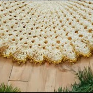 May include: A white crocheted Christmas tree skirt with a gold beaded trim.