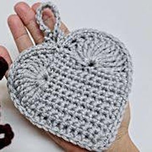 May include: Two crocheted heart-shaped ornaments, one in burgundy and one in silver. Both have a loop at the top for hanging.