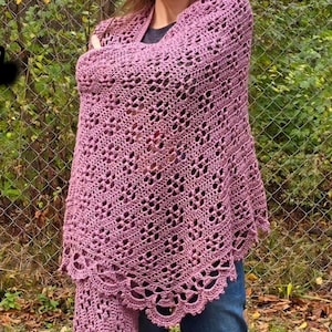 May include: A mauve crochet wrap with an openwork pattern. The wrap is worn over the shoulders and features a scalloped border. The image includes the text "Lena" Wrap.