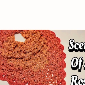 以下が含まれることがあります： オレンジと赤の色合いのクロシェのショールで、縁はギザギザになっています。ショールはバラのようなステッチパターンで作られています。