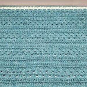 May include: A teal blue crocheted baby blanket with a white border.
