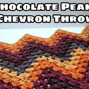 May include: A crocheted chevron throw blanket in shades of brown, orange, and grey. The blanket is made with a chunky yarn and has a textured, bumpy surface. The title "Chocolate Peaks Chevron Throw" is displayed above the blanket.