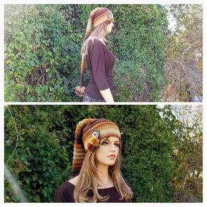 May include: A brown, orange and beige crocheted hat with a long tail and a button on top. The hat is being worn by a person with long brown hair.